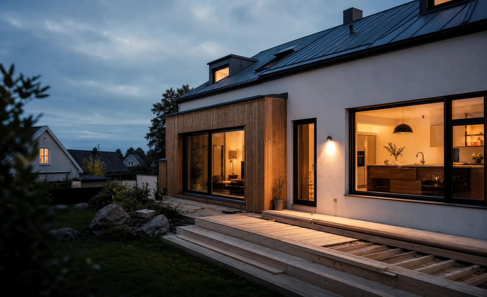Modern tillbyggnad i trä på ett svenskt hus i skymningsljus